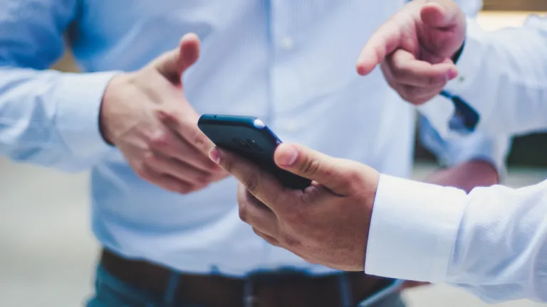 A person showing information on their phone to another person.