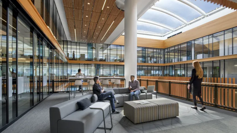 MTC employees meeting and working in a lounge in the sunny central atrium of the 375 Beale Street office.