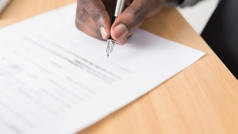 Man's hand signing document.