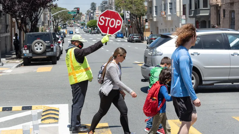 A crossing guard helps a family cross the street safely.