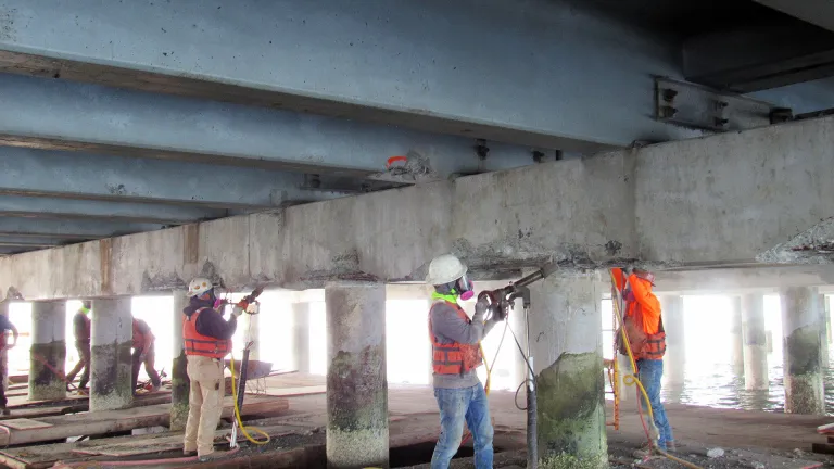 Crews performing bridge maintenance on the underside of the San Mateo-Hayward Bridge.
