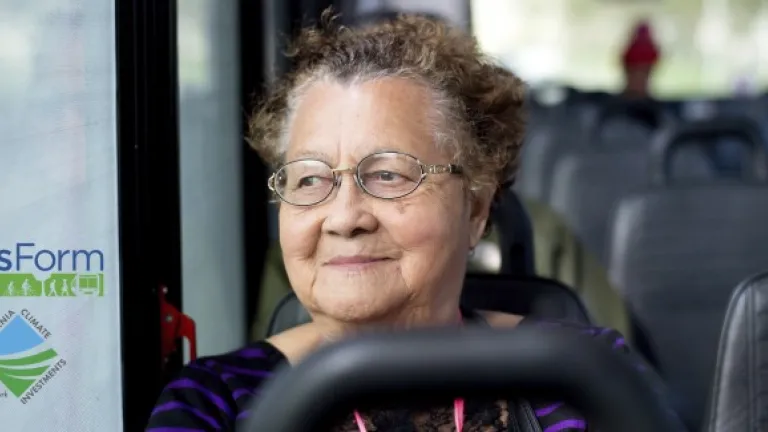 Woman riding a shuttle bus, with overlaid logos for TransForm and California Climate Investments