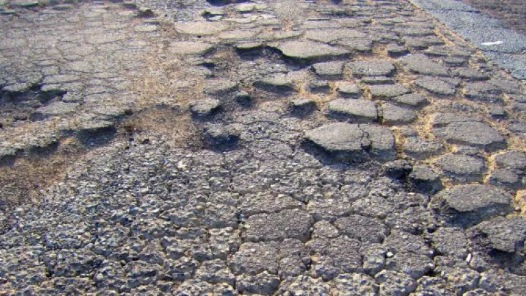 Image shows failed pavement, marked by potholes and alligator cracking