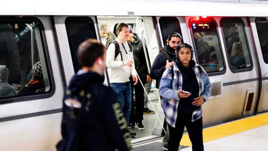 A visually impaired BART rider exits a train onto the platform.