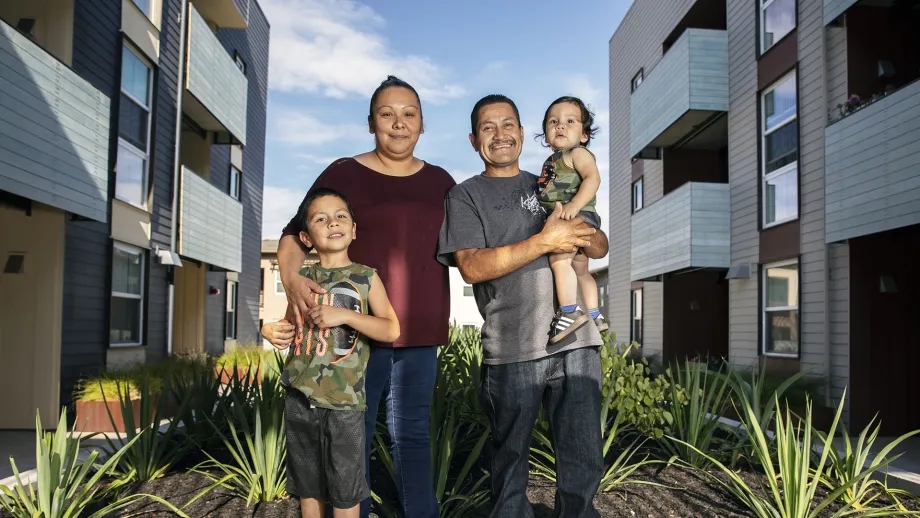 Portrait of a happy family standing outside their apartment complex.